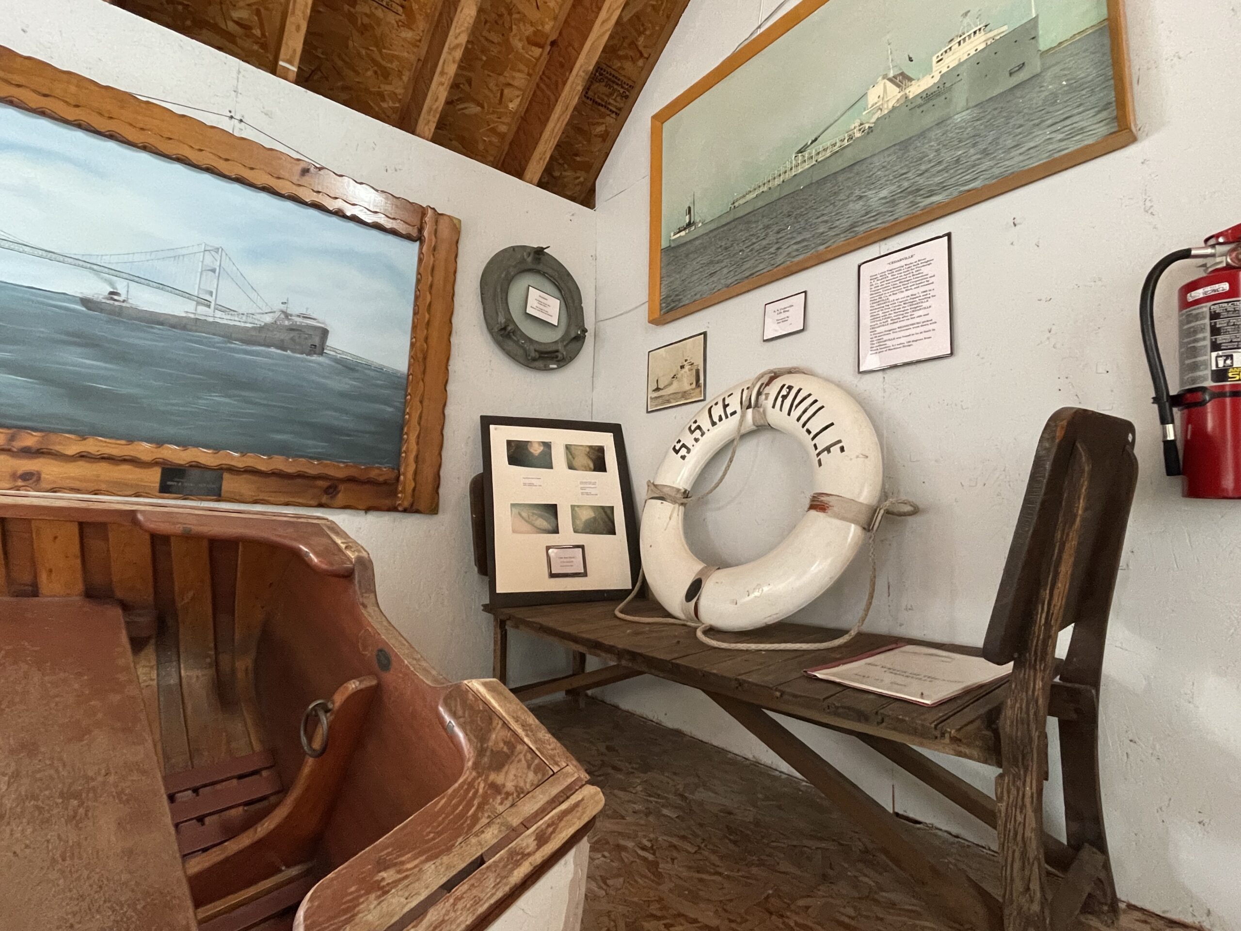 A museum display featuring maritime artifacts including lifebuoys, ship paintings, a wooden boat, and various historical documents.