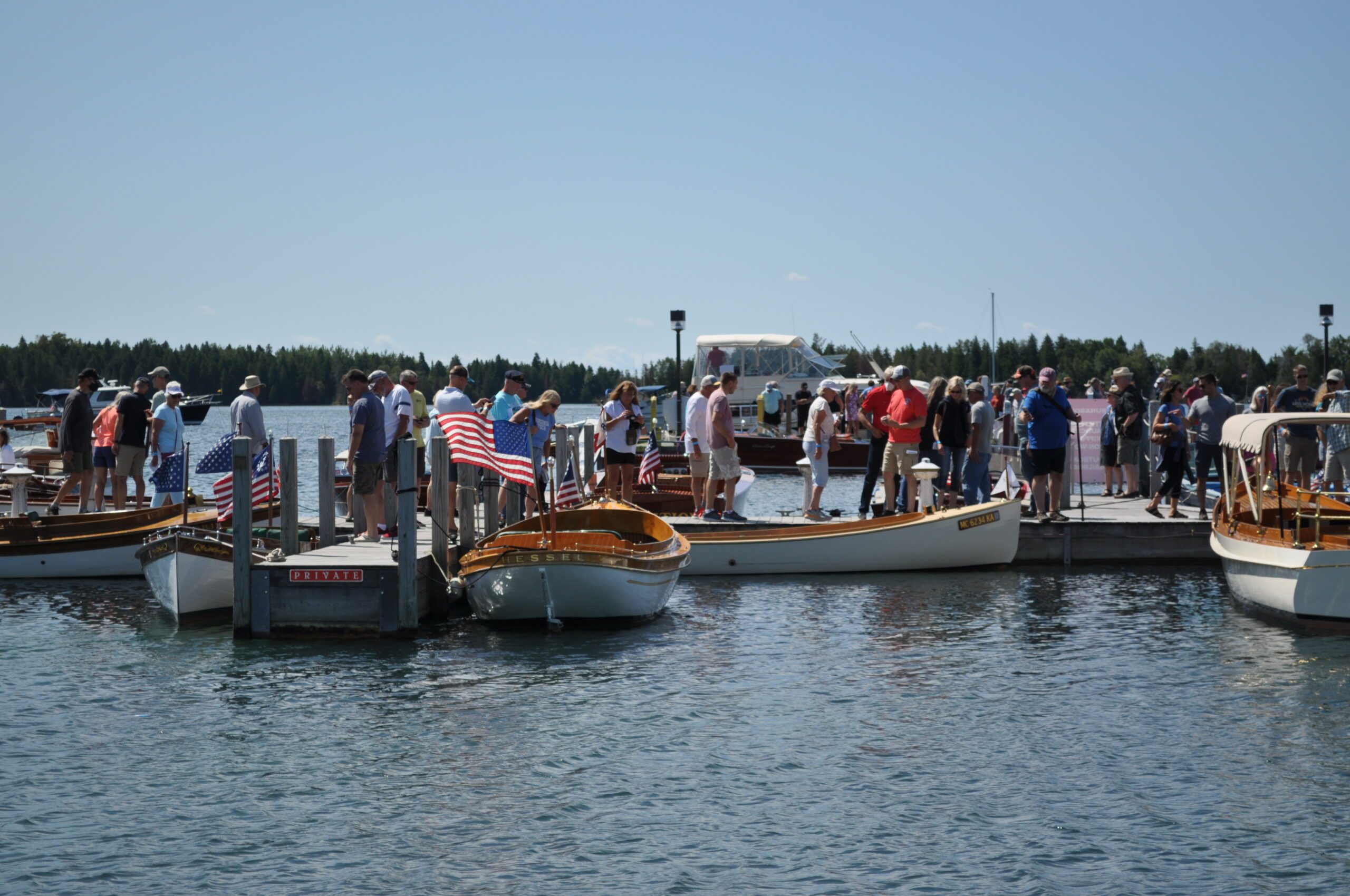 People gather on a dock viewing wooden boats.