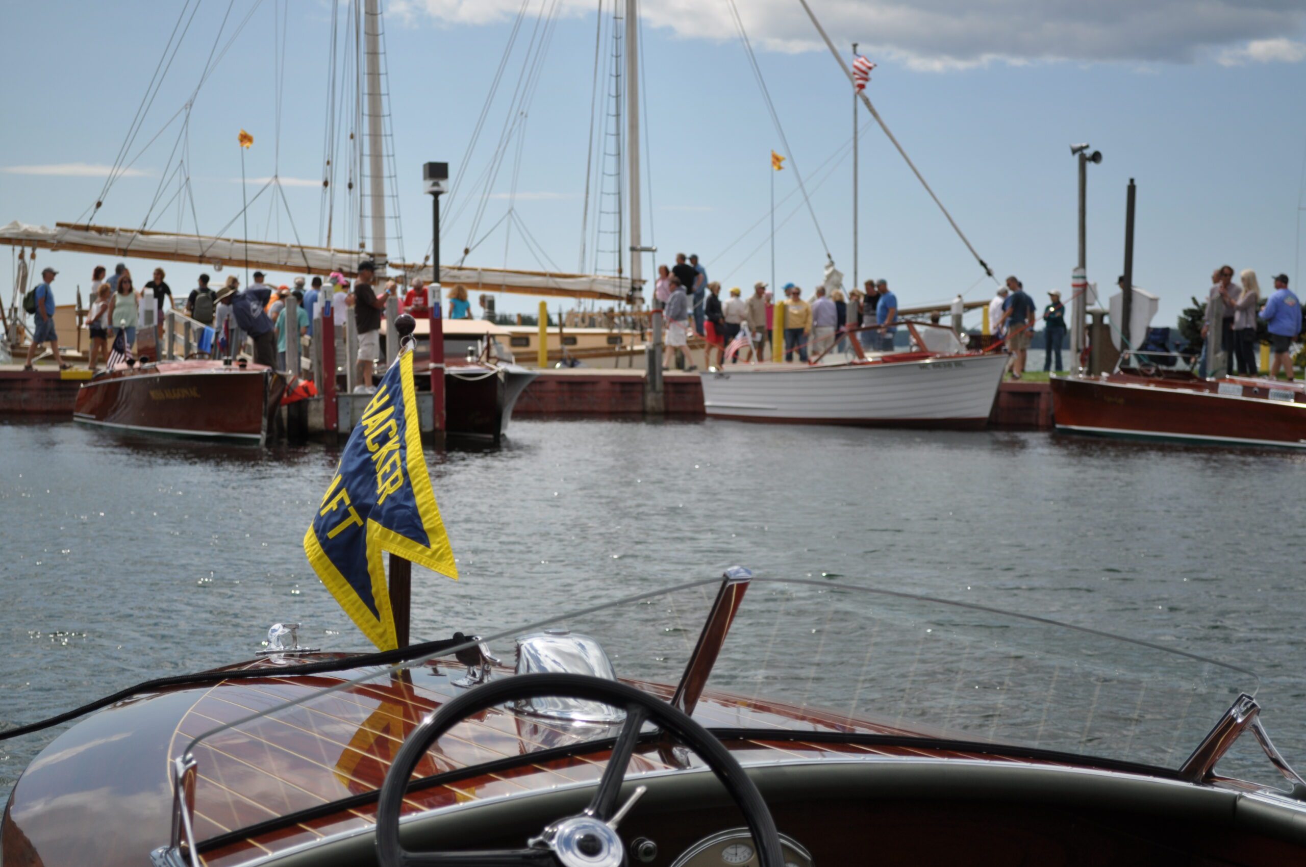 View from a boat at a dock with people and boats in the background under a cloudy sky.