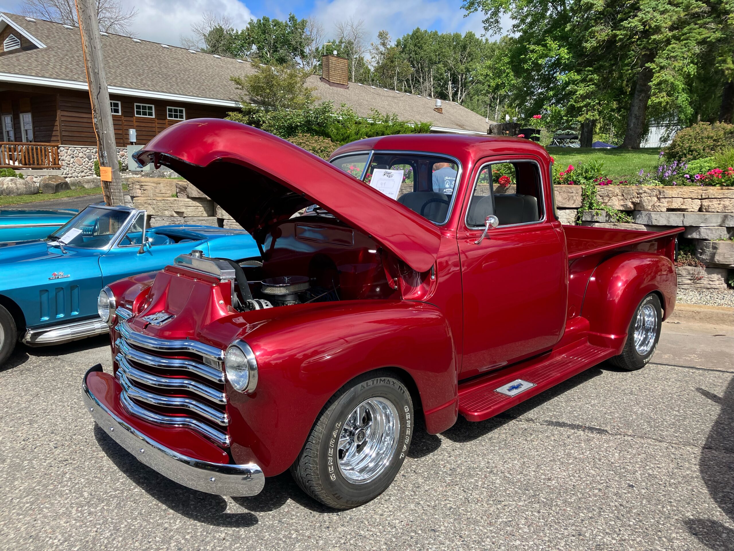 A classic red vintage truck with its hood open, showcasing its engine.