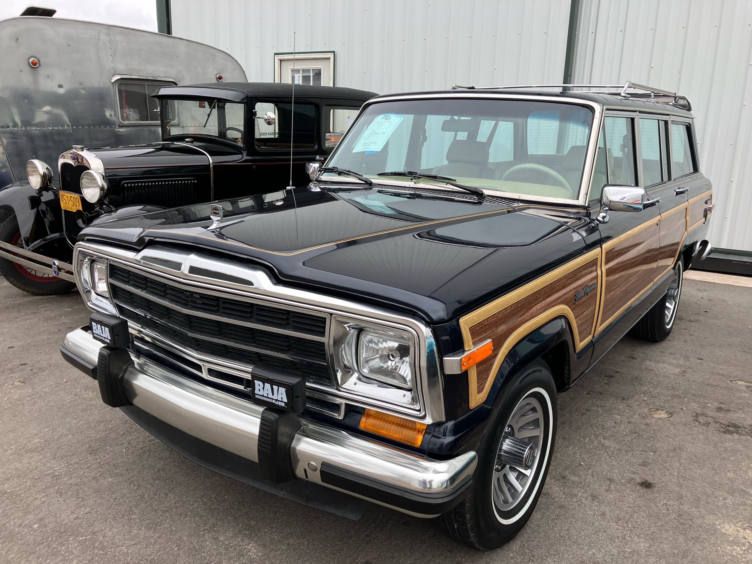 A vintage black Jeep Grand Wagoneer with wood paneling.