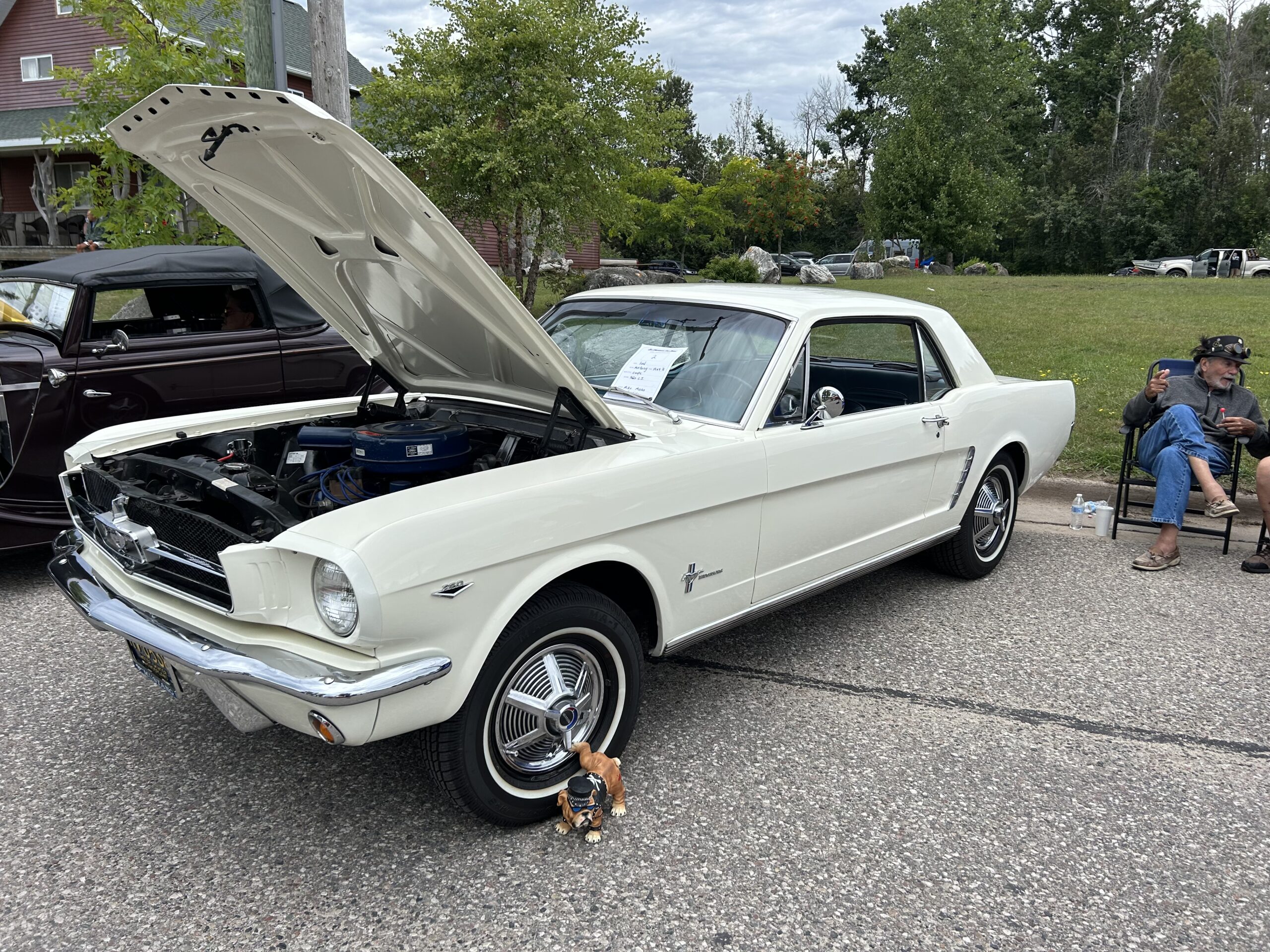 A white classic Ford Mustang with the hood open.